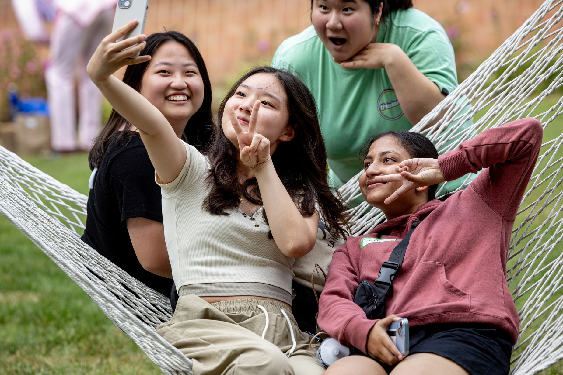 Four students in and around a hammock pose for a group selfie