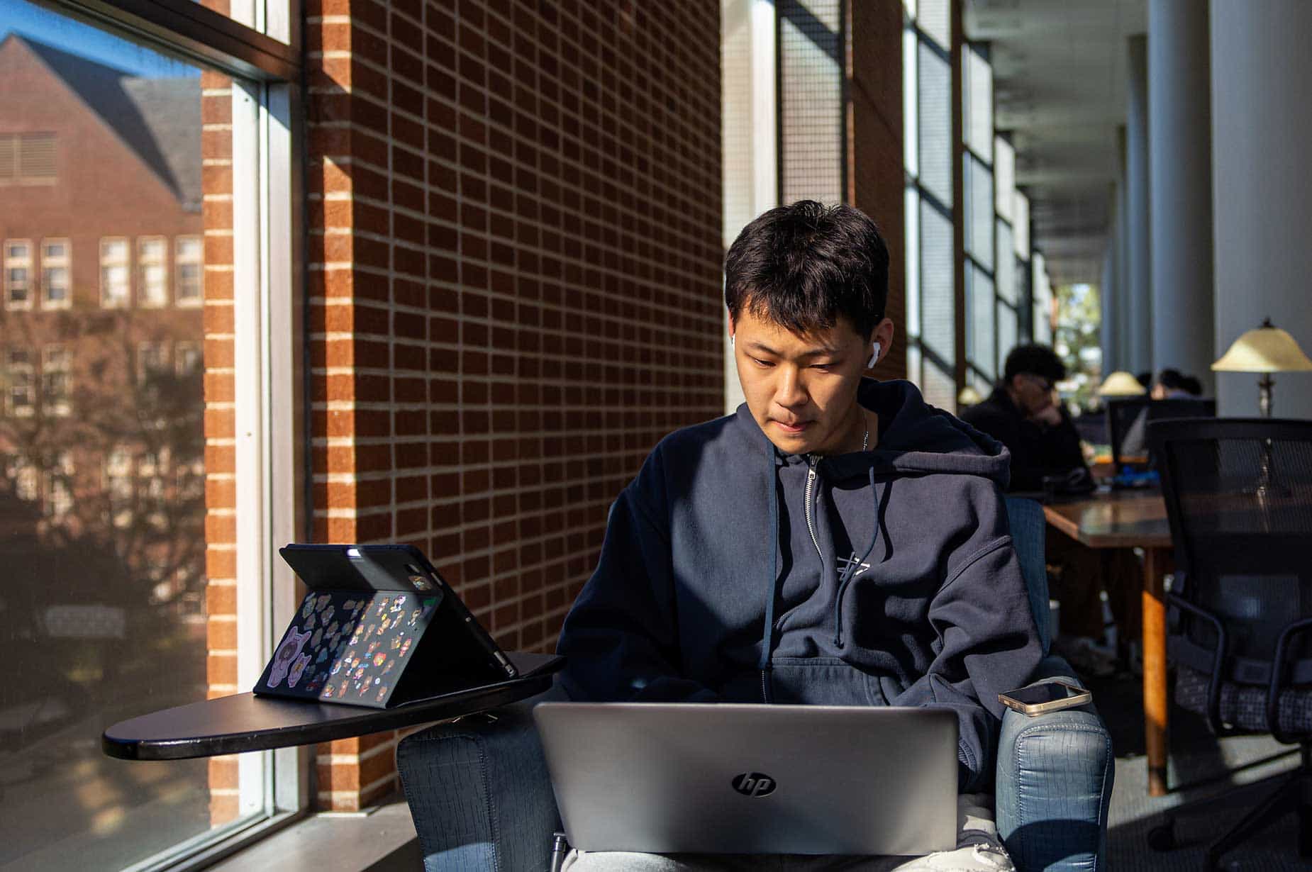 A male SLU student works on a laptop while sitting in Pius XII Memorial Library.