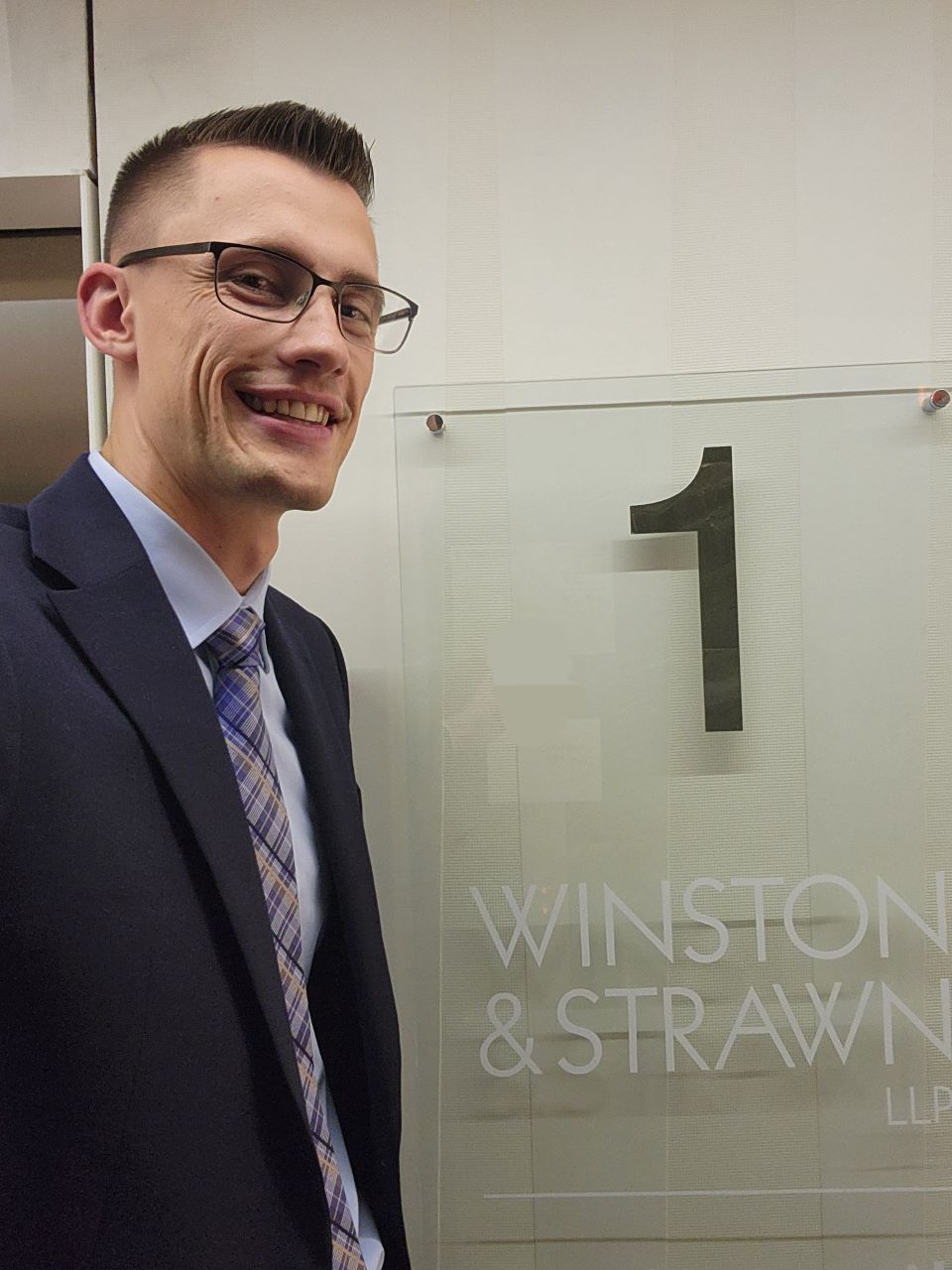 Charlie Kruljac poses at the entrance of a law firm