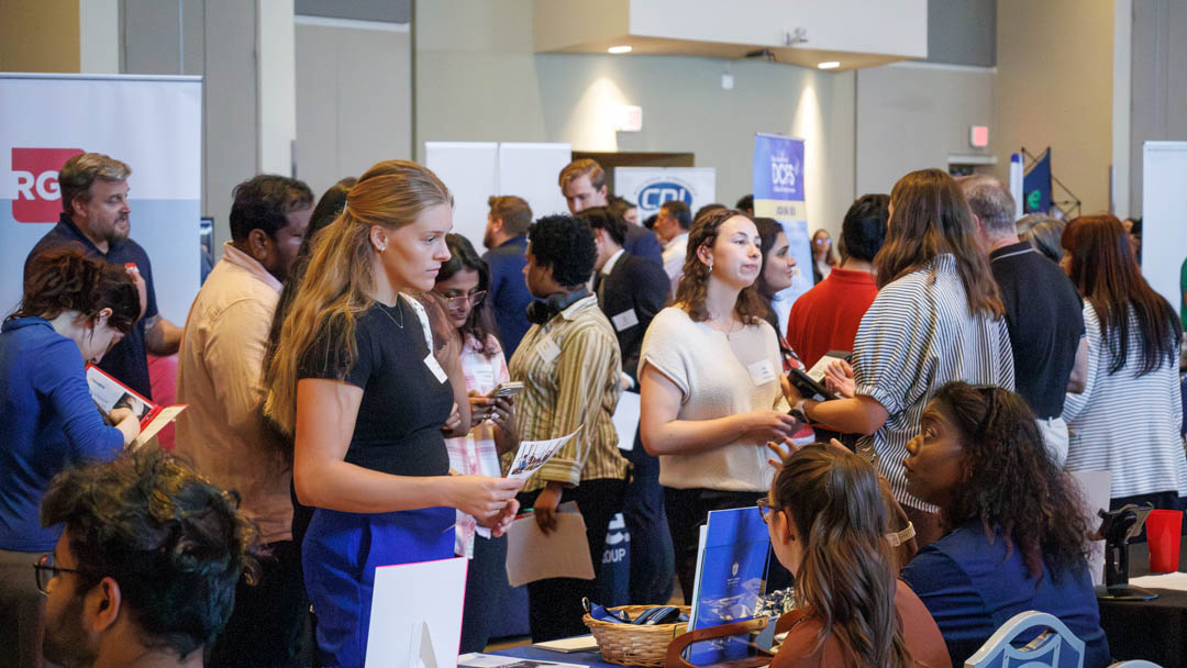 A crowd of SLU students standing in groups and in line at a carreer fair on campus inside a conference room